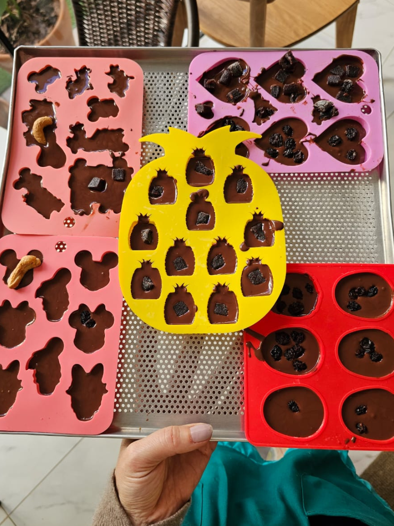 Chocolates sendo preparados em formas de silicone por crianças. 
