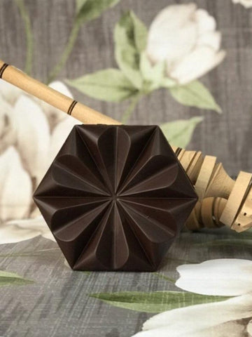 Chocolate de metate 100% sobre a mesa com fundo florido.