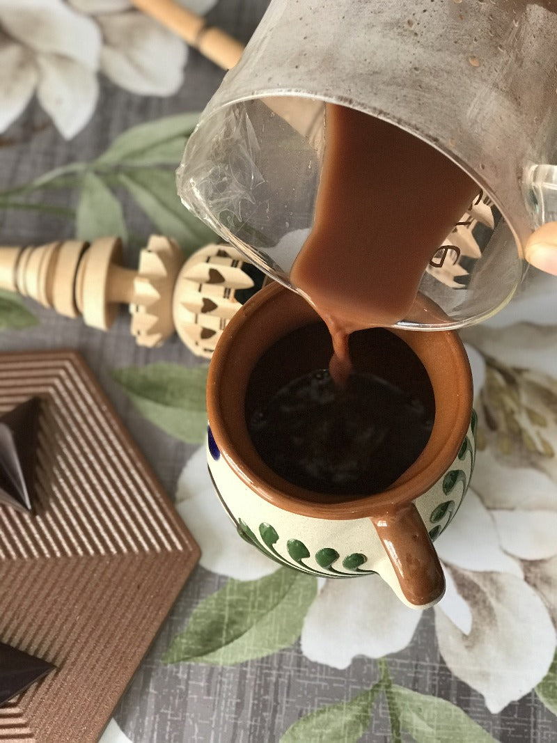 Chocolate de metate pronto em uma xícara e em barra sobre o pirex.